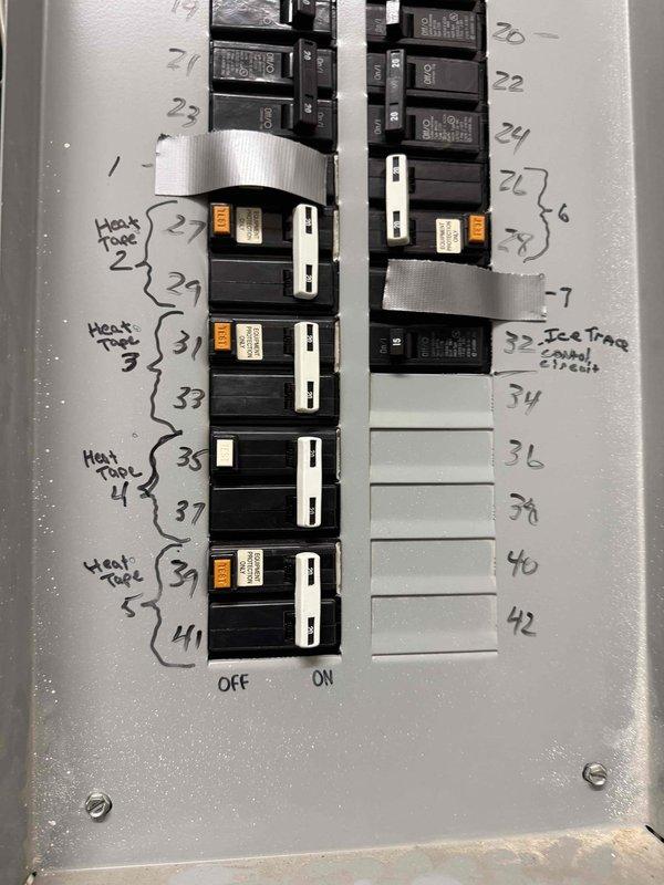Performed diagnostic assessment of non-functional heat tape system on roof. Inspected electrical panel where multiple heat tape circuits (labeled 2-5) were identified and found to be energized. Verified power reaching junction boxes for the two non-operational zones flanking the front entry. Determined issue was not electrical in nature and advised management to contact their dedicated heat tape maintenance vendor for further resolution.