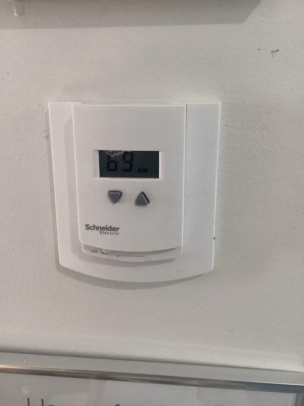 Diagnosed thermostat calibration issue with Schneider Electric unit showing 69°F while actual room temperature measured at 65.8°F with Taylor digital thermometer. Replaced faulty thermostats to resolve temperature differential problem that was preventing system from reaching setpoint.