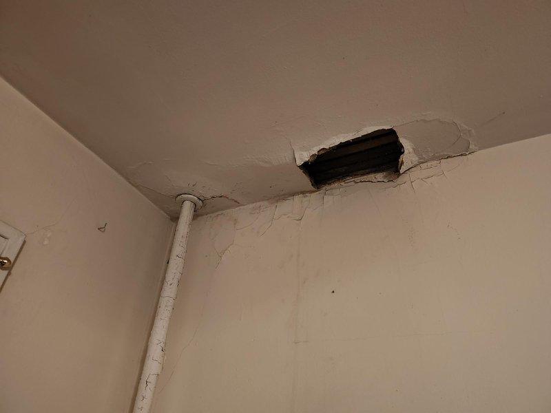 Investigated ceiling leak reported by resident that occurs intermittently with radiator "clanking" sounds. Accessed the site using provided lockbox codes and inspected the existing ceiling opening. Enlarged the access hole to better examine plumbing infrastructure and identified water damage consistent with an intermittent supply line leak. Repaired the compromised pipe connection and documented the condition with photos showing the extent of ceiling damage and affected wall areas.