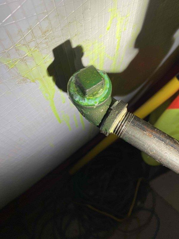 Conducted leak search on previously installed furnace system and identified refrigerant leak at metal pipe fitting, evidenced by significant green dye staining on surrounding white surface. Located primary leak point at threaded connection where corrosion was visible and refrigerant dye had accumulated and dripped onto adjacent surfaces.