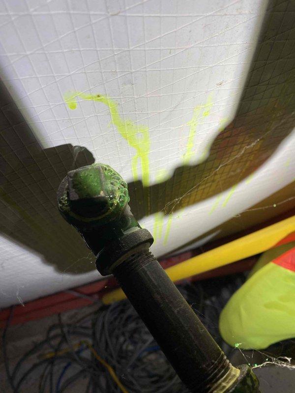 Conducted leak search on previously installed furnace system and identified refrigerant leak at metal pipe fitting, evidenced by significant green dye staining on surrounding white surface. Located primary leak point at threaded connection where corrosion was visible and refrigerant dye had accumulated and dripped onto adjacent surfaces.