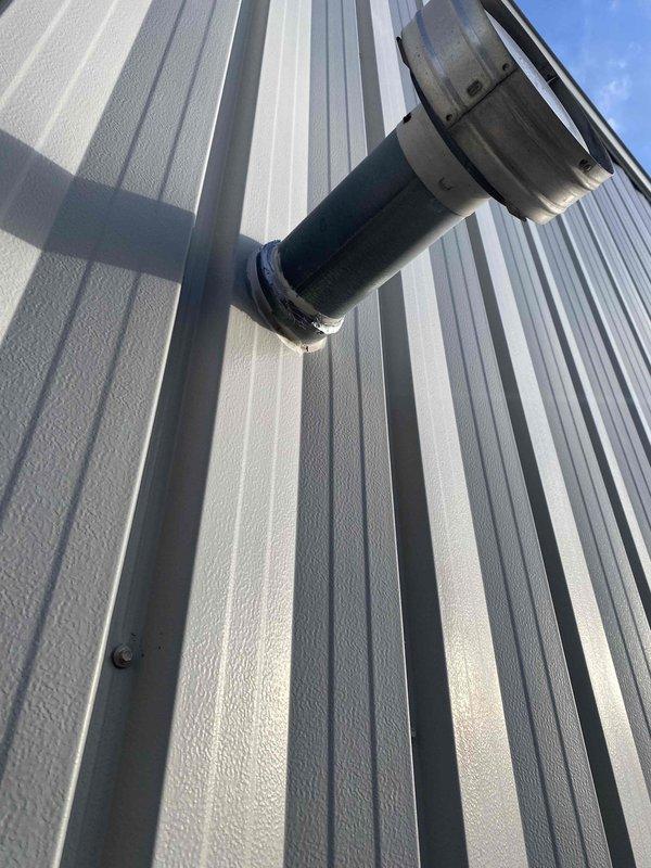 Completed code correction on unit heater by properly sealing all single wall vent joints per manufacturer's instructions for Cat. III configuration. Documented work with before/after photographs of the installation, ensuring proper venting through exterior wall panel with appropriate flange connections and sealed junction points.