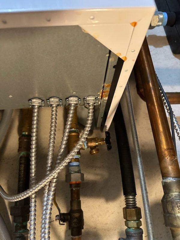 Responded to maintenance callback for water leak originating from boiler system. Upon inspection, identified active leakage evidenced by rust-colored staining on concrete floor surrounding boiler piping connections. Inspected all copper piping, ball valves, flexible metallic conduits, and heat exchanger components for source of leak and verified proper operation of system following previous maintenance service performed earlier this season.