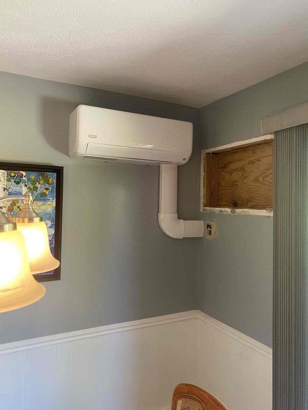 Completed installation of a two-head ductless mini-split system with a 12K BTU head mounted in the dining room near the existing through-the-wall unit and a 9K BTU head installed on the back wall of the rear bedroom. Utilized existing wiring and breaker from the through-the-wall AC unit, installed interior cover plate, and ran line hide along joists with whip connection to disconnect for the dining room head using 20-foot line set with refrigerant lines and drain routed through the side of the unit. Installed 30-foot line set for the bedroom head with outdoor unit mounted on selected pad or wall bracket, ran white plastic line covers vertically along walls to conceal refrigerant lines, and completed all electrical connections including 30-amp disconnect and control wiring.
