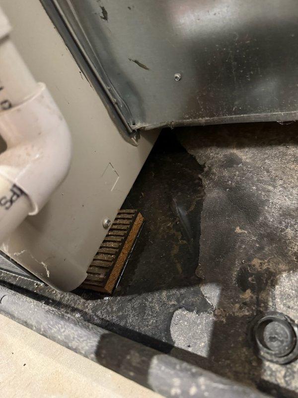 Responded to a water leak complaint at the furnace following recent seasonal maintenance. Inspected the unit and found moisture, corrosion, and debris accumulation at the base of the cabinet near the condensate drain piping and lower vent area, indicating a condensate drainage issue. Verified the condensate drain assembly and surrounding area to isolate the source of the leak and documented the unit's condition for the service record.