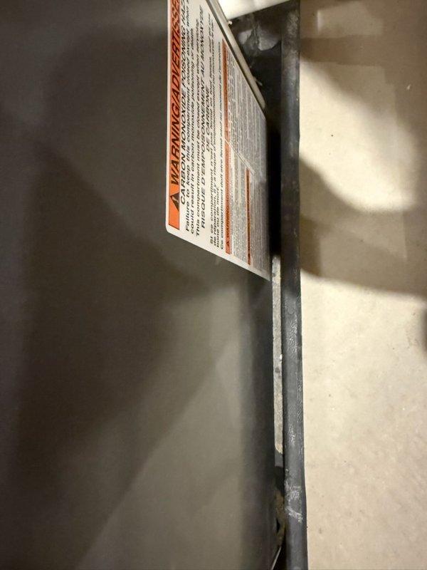 Responded to a water leak complaint at the furnace following recent seasonal maintenance. Inspected the unit and found moisture, corrosion, and debris accumulation at the base of the cabinet near the condensate drain piping and lower vent area, indicating a condensate drainage issue. Verified the condensate drain assembly and surrounding area to isolate the source of the leak and documented the unit's condition for the service record.