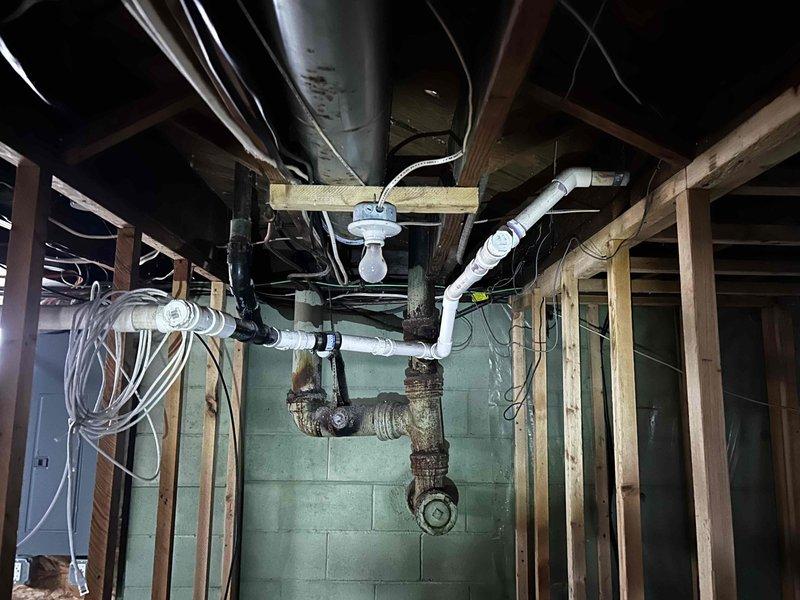 Inspected property after house fire to provide quotation for replacement of severely corroded cast iron drain lines and damaged water supply piping. Documented extensive deterioration at pipe joints with visible white-green mineral deposits and rust throughout the basement plumbing system. Water heater remains in good condition and was not included in replacement estimate.