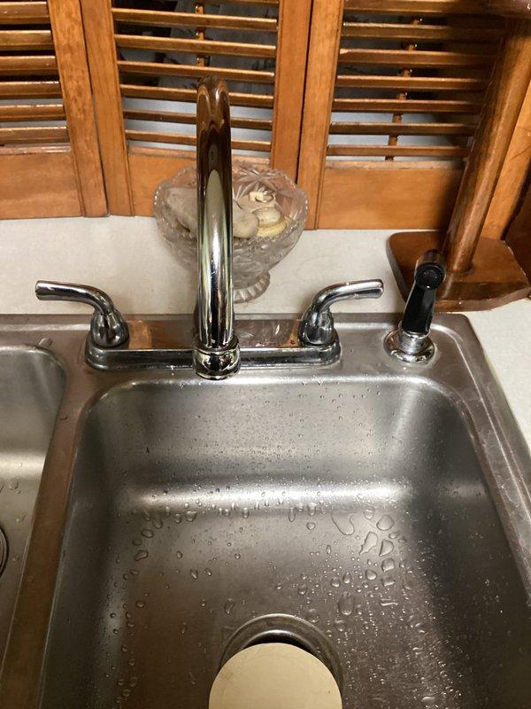 Responded to service call regarding low water pressure at kitchen faucet. Upon inspection, determined blockage in faucet aerator was restricting water flow. Removed aerator, cleaned calcium and sediment buildup, and reinstalled. Tested water flow which returned to normal pressure and function.