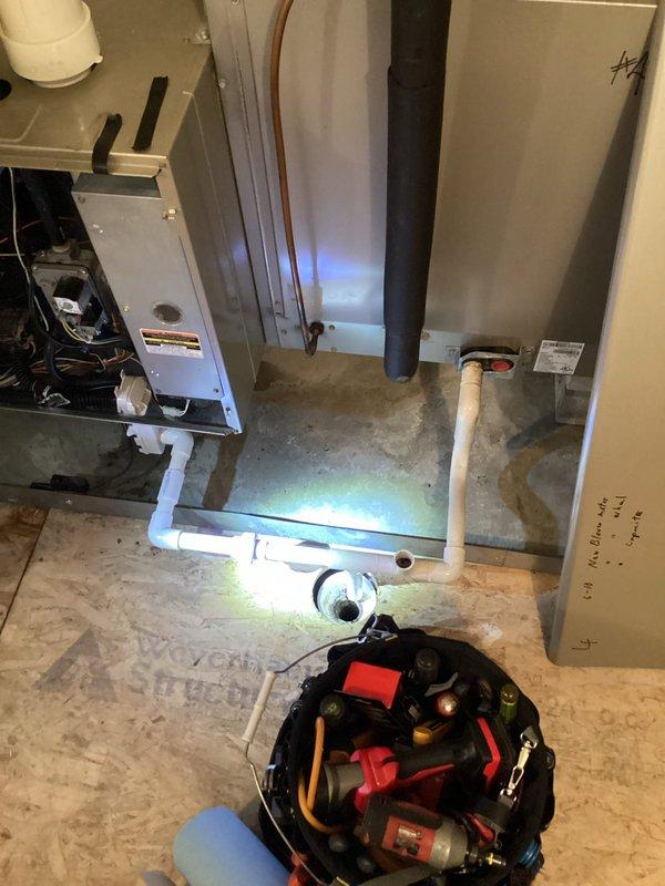 Performed follow-up service call for heating system not maintaining set temperature (72°F set, 64°F actual). Inspected drainage system previously serviced for water backup in inducer motor. Found PVC condensate drain line properly connected to floor drain with no current blockages. Examined furnace with panels removed to verify inducer motor operation and confirmed proper draft. System is now heating correctly with no water accumulation in components.
