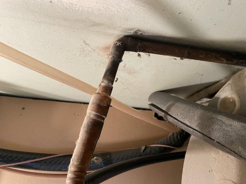 Responded to service call for non-functioning tanked water heater, approximately 5-6 years old. Diagnosed ignition failure and repaired minor water leak observed at copper pipe connections. Inspected aging copper piping showing oxidation and patina development, particularly at joints and 90-degree bends, and verified proper function of pressure relief valve system.