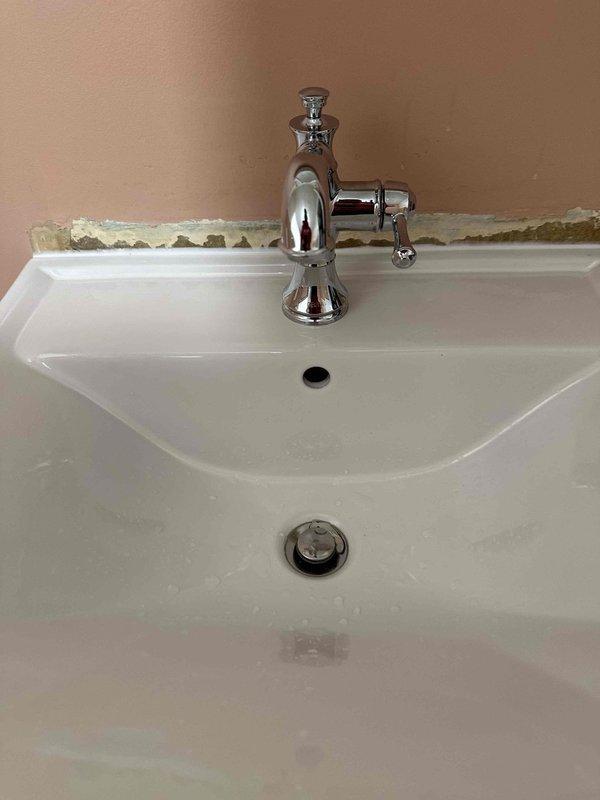 Picked up and installed new pedestal sink and chrome single-handle faucet. Connected water supply lines and ensured proper drainage. Noted existing wall damage behind sink where drywall is deteriorating along the backsplash area.
