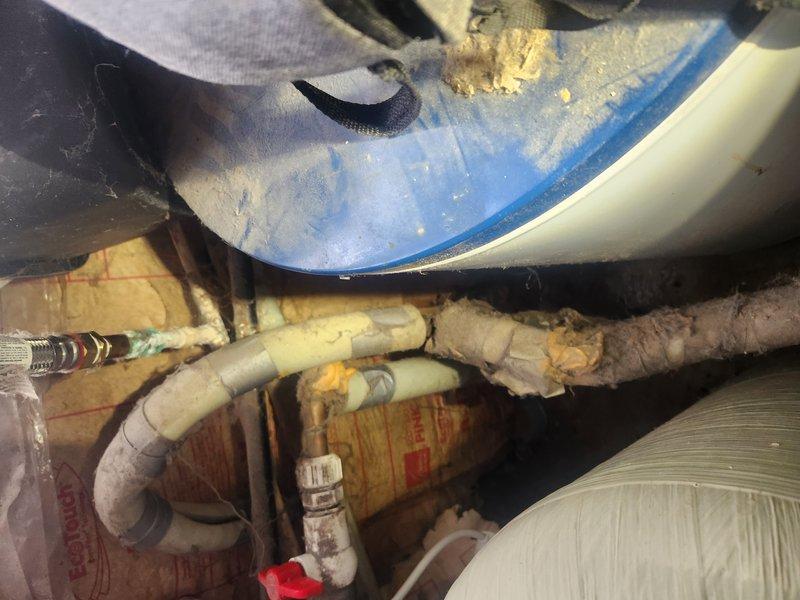 Responded to emergency call for active water leak at slab level in the home. Upon inspection, found severely degraded plumbing infrastructure with significant moisture damage, including deteriorated insulation and corrosion around pipe connections. Repaired burst PVC pipe section and replaced damaged fittings near water heater connection point, restoring system integrity after water service had been shut off.