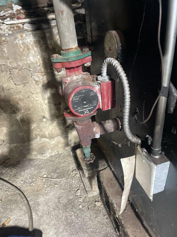 Conducted comprehensive assessment of client's aging LP boiler hot water heating system. Observed original installation mounted on concrete blocks with connected galvanized ductwork, copper piping, and red circulator pump showing significant wear and corrosion. System remains operational but has reached end of service life; documented deteriorating components and electrical connections for replacement estimate.