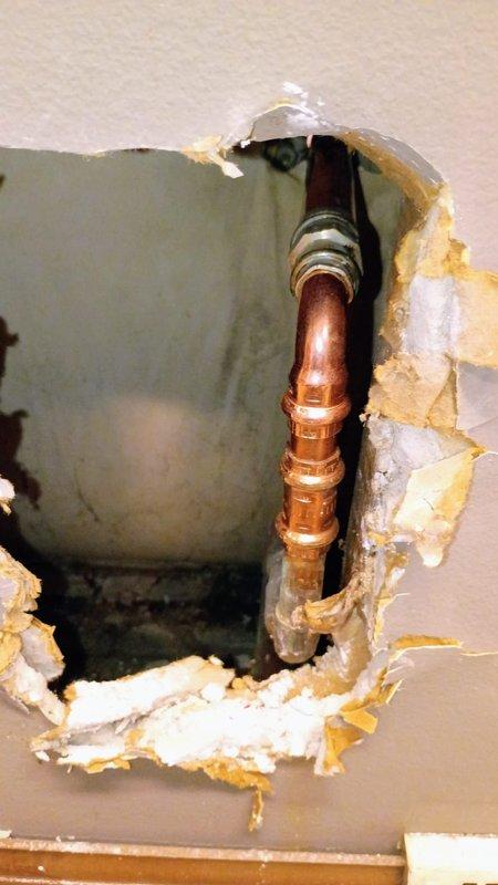 Responded to emergency call for water leak in office. Upon inspection, identified a burst copper pipe running from inside office to exterior spigot. Customer had shut off water supply and cleaned standing water prior to arrival. Accessed damaged section through wall, documented extensive damage with exposed copper pipe and coupling. Repaired burst pipe section and restored water service to building.