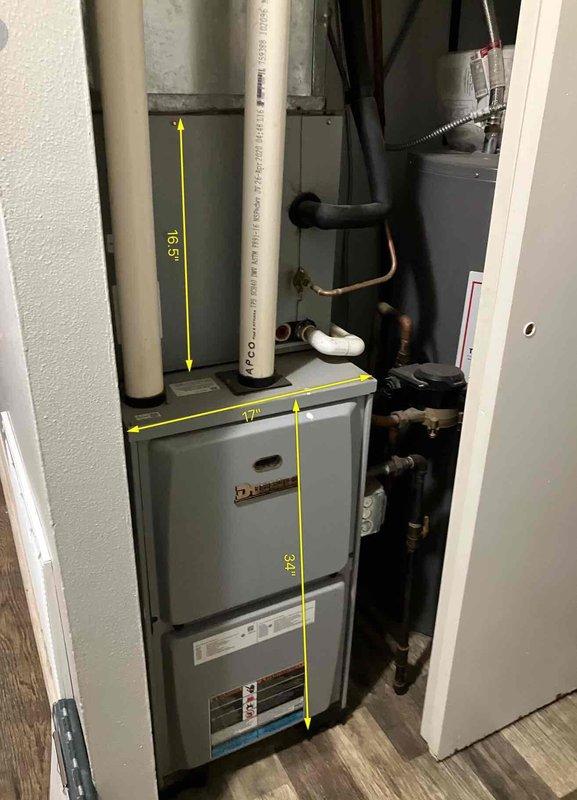 Conducted assessment of 5-year-old Ducane furnace system (17" width x 34" height) with 16.5" vertical ductwork and connected refrigerant lines for AC unit replacement. Exterior inspection revealed weathered outdoor condenser unit installed adjacent to wooden deck with proper drainage connection. Photos documented both indoor furnace configuration and outdoor unit placement for comprehensive replacement estimate.