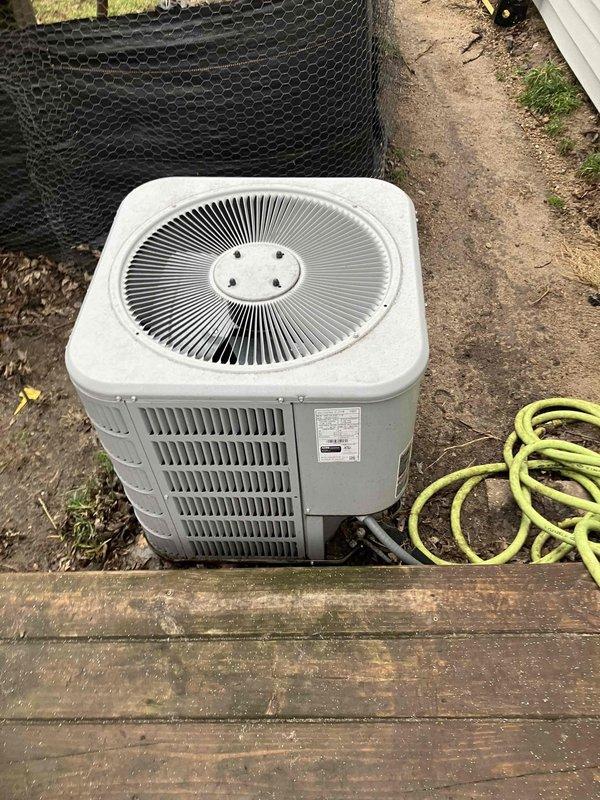 Conducted assessment of 5-year-old Ducane furnace system (17" width x 34" height) with 16.5" vertical ductwork and connected refrigerant lines for AC unit replacement. Exterior inspection revealed weathered outdoor condenser unit installed adjacent to wooden deck with proper drainage connection. Photos documented both indoor furnace configuration and outdoor unit placement for comprehensive replacement estimate.