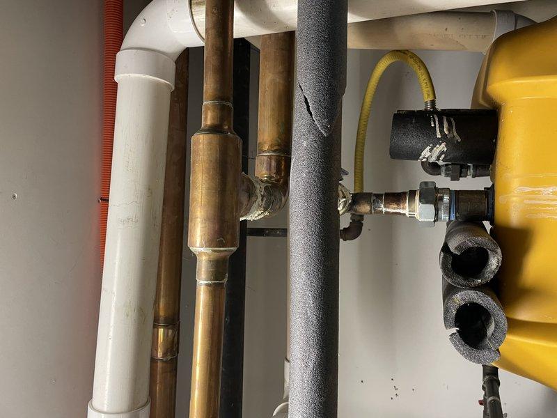 Inspected copper piping system identified by code enforcement for patina repair requirements. Evaluated extensive oxidation and corrosion on copper pipe fittings and joints, particularly at elbow connections. Documented condition of the plumbing network including affected copper components, PVC sections, and associated insulated lines for remediation planning.