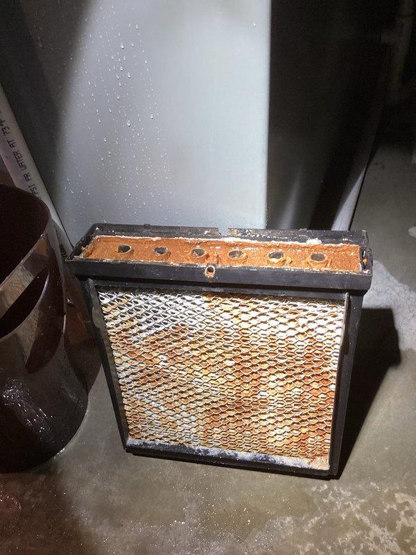 Responded to service call regarding basement humidifier leaking onto floor. Upon inspection, found significant corrosion on humidifier components and severely clogged filter with extensive dirt buildup. Replaced deteriorated humidifier filter and serviced corroded metal components to resolve water leakage issue.