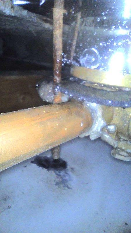 Responded to a service call for a shower leaking when hot water is running and a secondary leak in basement. Inspection revealed significant frost and ice buildup at a pipe joint connection in the utility area, with visible moisture and water damage on the floor beneath. Also identified connection issues between copper and PVC piping in the ceiling area where insulation was compromised, contributing to the leakage problems.