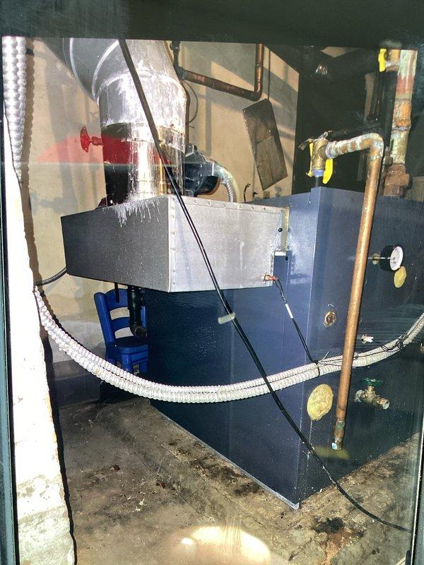 Inspected aging heating system in response to no-heat complaint. Found pressure regulator showing signs of oxidation with multiple shut-off valves in the plumbing installation. Examined the boiler unit with connected copper piping, pressure gauge, and insulated ductwork for proper operation.