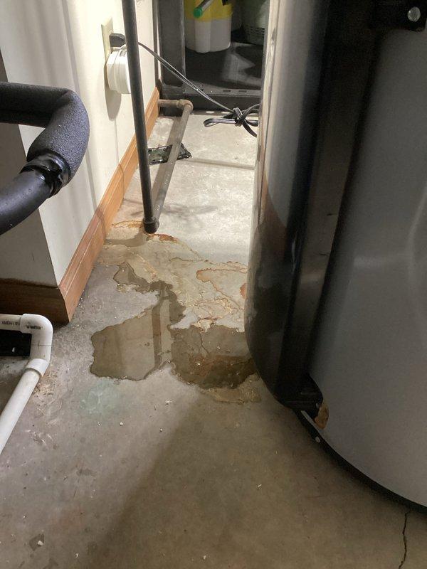 Performed scheduled A/C maintenance under membership plan and identified significant water accumulation on utility room floor. Upon inspection, determined water source was from the water heater, not the HVAC system. Advised customer that a plumber should be contacted to address the water heater leak as evidenced by substantial brown water puddles and concrete staining around the tank base.