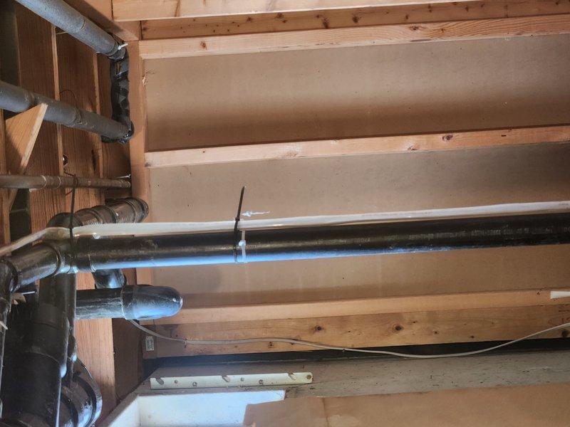 Responded to a plumbing emergency where a broken shower floor drain was causing water to leak into the basement. Upon inspection, identified failed drain assembly and deteriorated piping connections in the crawl space above the basement. Accessed the affected area through the attic/crawl space and examined the galvanized steel supply lines and black ABS drain piping system. The metal drain flange penetrating through the foundation wall showed significant corrosion and compromised seals at the connection points. Assessed the entire drainage configuration, including the elbow joints and horizontal drain runs, to determine the extent of the failure. Documented the condition of the existing plumbing infrastructure, including the aged drain fittings and deteriorated coupling connections between the metal flange and plastic piping system.