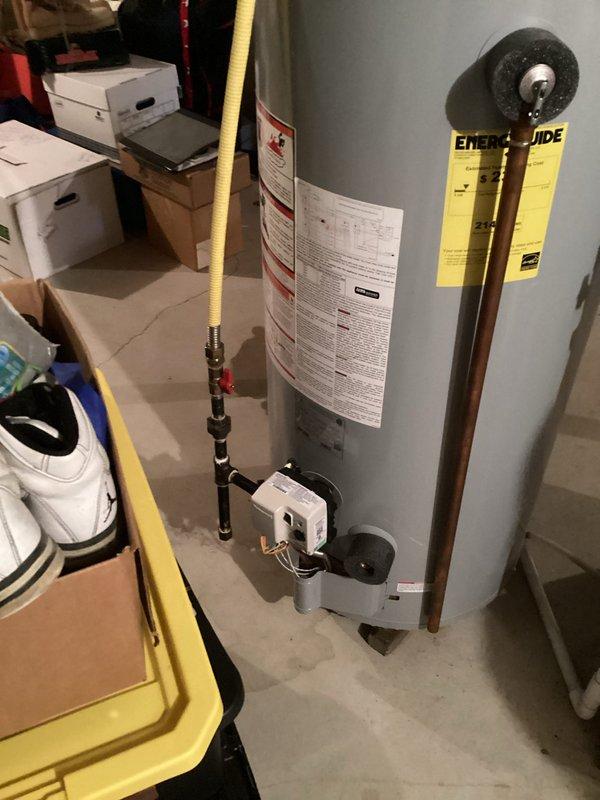 Conducted on-site evaluation of residential gas water heater located in basement utility area. Inspected tank-style water heater with atmospheric venting, confirmed gas fuel source via yellow flexible gas line connection, and assessed copper supply piping and electrical control components. Documented equipment condition and specifications to provide replacement estimate.