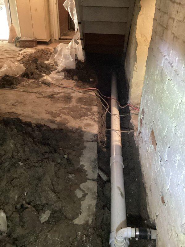 Completed crawl space pipe repair work involving burst pipe remediation. Excavated and prepared trenching in basement area, installed new white PVC drainage piping with proper securing straps and clamps, and finished quoted plumbing repairs. Containment measures were utilized throughout the work area to minimize dust and debris during the installation process.