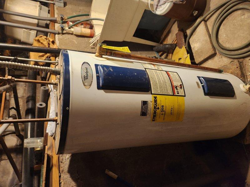 Responded to service call for 13-year-old Whirlpool water heater with no hot water production. Upon arrival, conducted comprehensive diagnostic assessment of the unit and surrounding plumbing infrastructure. Inspected water heater components including heating elements, thermostat operation, and gas/electrical connections. Evaluated copper supply lines and brass fittings at top of tank for proper function and identified slow drip leak in basement plumbing system. Documented equipment condition through photographic evidence showing unit positioning, label information, and connection points. Assessed age-related wear on tank exterior, piping connections, and surrounding concrete foundation. Provided technical evaluation of water heater performance issues and separate plumbing leak to determine relationship between failures and recommend appropriate repair or replacement solutions.