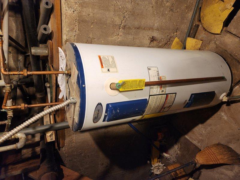 Responded to service call for 13-year-old Whirlpool water heater with no hot water production. Upon arrival, conducted comprehensive diagnostic assessment of the unit and surrounding plumbing infrastructure. Inspected water heater components including heating elements, thermostat operation, and gas/electrical connections. Evaluated copper supply lines and brass fittings at top of tank for proper function and identified slow drip leak in basement plumbing system. Documented equipment condition through photographic evidence showing unit positioning, label information, and connection points. Assessed age-related wear on tank exterior, piping connections, and surrounding concrete foundation. Provided technical evaluation of water heater performance issues and separate plumbing leak to determine relationship between failures and recommend appropriate repair or replacement solutions.