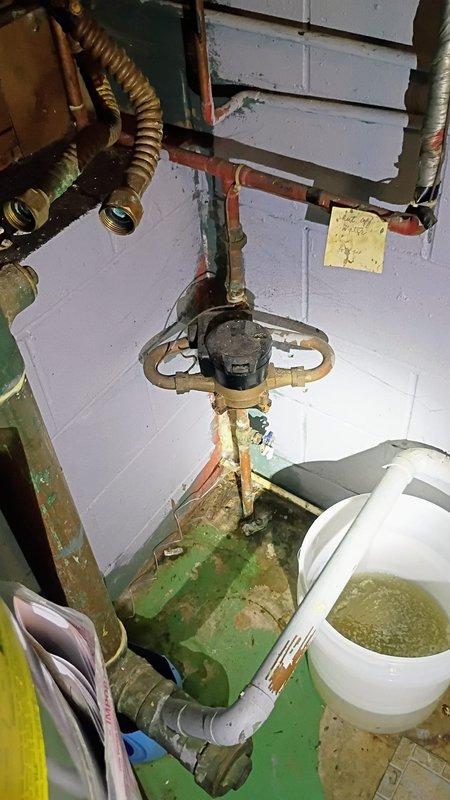 Responded to basement water leak complaint and performed comprehensive diagnostic inspection of plumbing system. Located active leak at circulator pump assembly with visible water accumulation and moisture damage to surrounding floor surfaces. Identified corroded copper piping connections and compromised valve seals contributing to water intrusion, with evidence of mineral deposits and long-term moisture exposure on mechanical components. Documented existing conditions including deteriorated pump fittings, oxidized copper connections, and standing water in collection bucket. Provided estimate for necessary repairs including pump replacement, copper pipe refitting, and valve seal restoration as per customer's request for assessment only.