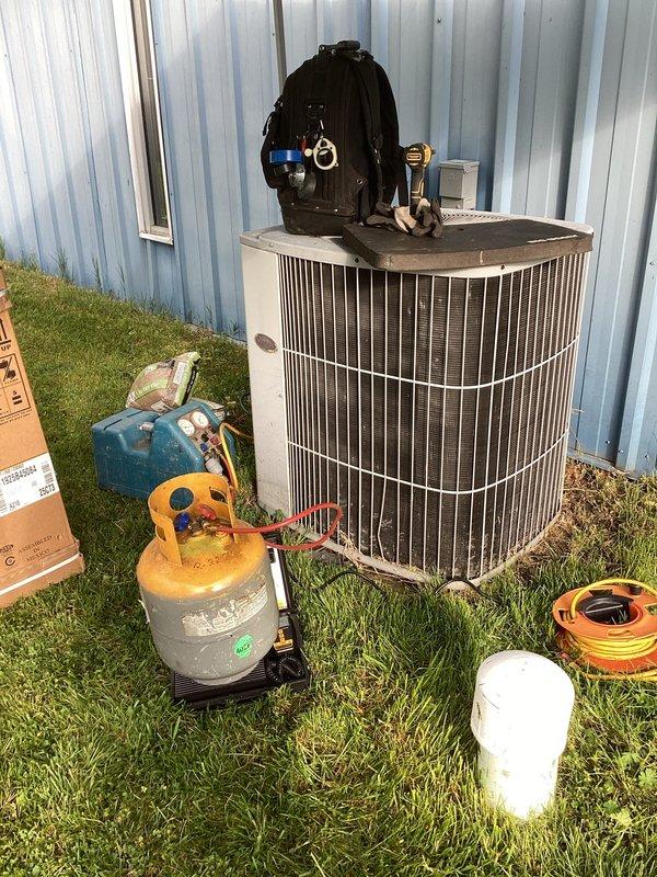 Completed installation of Lennox ML13 air conditioning system with outdoor condenser unit positioned on grade-level pad against exterior wall. Reused existing thermostat and indoor air handler, establishing refrigerant line connections between outdoor and indoor components. System was evacuated, charged to manufacturer specifications, and tested for proper operation with all electrical connections verified and secured.