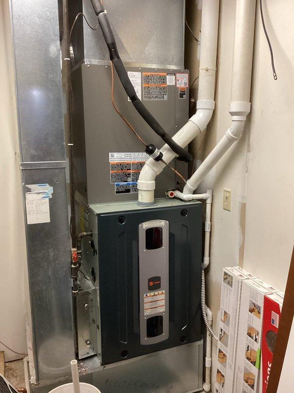 Completed installation of Lennox ML13 air conditioning system with outdoor condenser unit positioned on grade-level pad against exterior wall. Reused existing thermostat and indoor air handler, establishing refrigerant line connections between outdoor and indoor components. System was evacuated, charged to manufacturer specifications, and tested for proper operation with all electrical connections verified and secured.