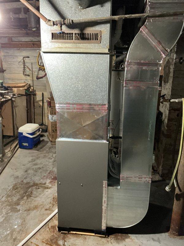 Completed installation of Lennox ML196 high-efficiency furnace with T4 programmable thermostat in basement location. Installation included full return drop kit with proper insulation and sealing, new chimney liner for venting, and connection of all ductwork components. Verified system operation with supply air temperature reading of 143.5°F, confirming proper heat exchanger function and airflow delivery. All components secured and insulated per manufacturer specifications.