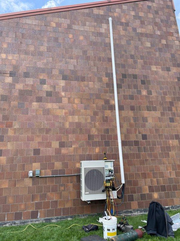 Completed installation of Lennox single-zone ductless mini-split system. Mounted outdoor condensing unit on exterior brick wall with refrigerant lines and electrical connections run along building facade, installed vertical PVC line set cover, and performed system startup with manifold gauge testing to verify proper refrigerant pressures and operational performance.