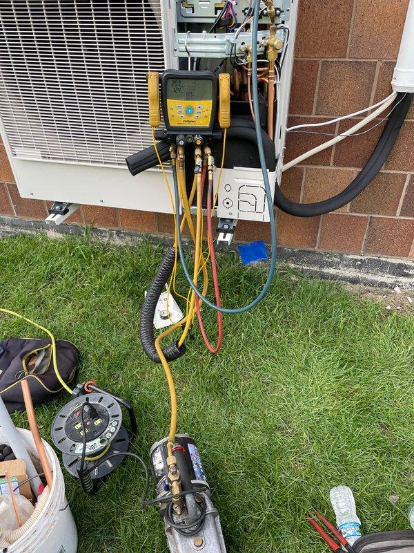 Completed installation of Lennox single-zone ductless mini-split system. Mounted outdoor condensing unit on exterior brick wall with refrigerant lines and electrical connections run along building facade, installed vertical PVC line set cover, and performed system startup with manifold gauge testing to verify proper refrigerant pressures and operational performance.