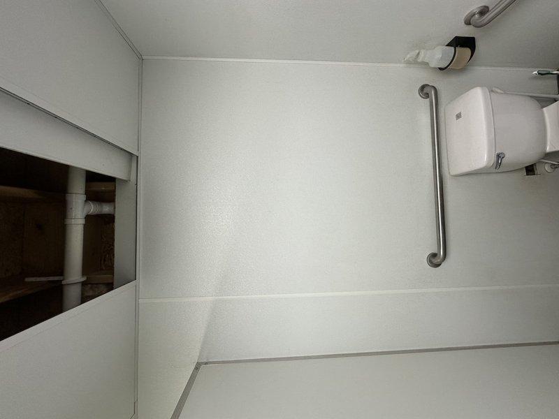 Returned to site to conduct detailed assessment and documentation of accessible restroom facilities for quoting purposes. Photographed existing toilet installation, ADA-compliant grab bar configuration, wall-mounted fixtures, and plumbing infrastructure including visible PVC drainage components. Documented current conditions of white partition walls, stainless steel safety rails, and dispenser mounting locations to provide accurate scope of work for upcoming service requirements.