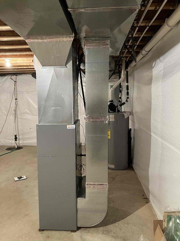 Conducted on-site assessment for HVAC system upgrade from standard 1-inch filter to media filter system to improve filter accessibility. Documented existing furnace and ductwork configuration in basement mechanical room, taking detailed measurements of vertical supply ducts and clearances for proper media filter cabinet sizing and installation planning. Photographed current equipment layout including furnace unit, ductwork dimensions, and available space for system modifications to prepare comprehensive replacement estimate.