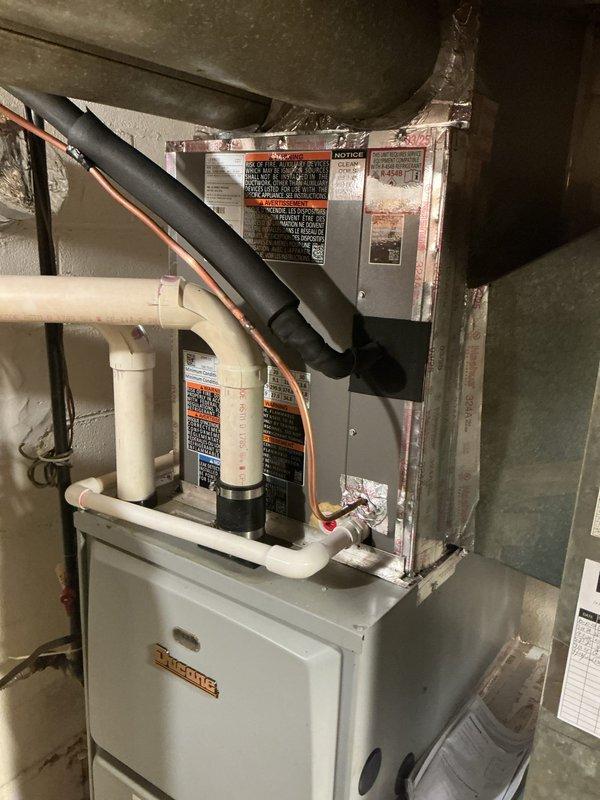Completed full air conditioning system installation including Lennox ML13KC1-030 condenser unit, CK40CT-30B cased evaporator coil, T4 thermostat, and condensate pump with tubing. Evaporator coil was removed from case to facilitate proper installation in basement utility area. All refrigerant lines were connected and insulated with black foam, PVC condensate drain lines were routed and secured, and electrical connections were completed including proper conduit installation. System was charged with refrigerant per manufacturer specifications, tested for proper operation, and thermostat was programmed and verified functional. All components are operating within normal parameters.