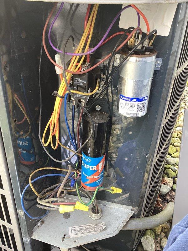 # HVAC Maintenance Service Completed

Performed comprehensive planned maintenance inspection on outdoor condensing unit as part of Gold Level service agreement. Conducted thorough visual inspection of all accessible components with unit access panel removed to evaluate internal electrical and mechanical systems.

Inspected dual capacitor assembly including silver run capacitor and SuperStarter hard start kit for proper operation and signs of deterioration. Verified all electrical connections throughout compartment, including multiple wire runs and terminal connections. Examined contactor relay assembly for contact wear and proper engagement. 

Assessed overall cleanliness of internal cabinet, noting accumulated dust and debris consistent with normal operation. Evaluated wire management and connection integrity of all colored wire runs including power supply and control circuits. Inspected wire connectors for secure attachment and signs of overheating.

Examined exterior condensing coil