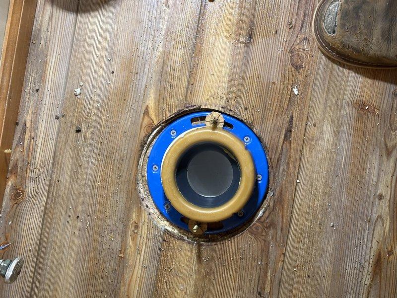 Replaced toilet flange on wooden subfloor in residential bathroom. Removed old deteriorated flange and installed new PVC flange assembly with blue mounting ring, securing it properly to subfloor with appropriate fasteners. Ensured flange was level and properly positioned for toilet reinstallation, with closet bolts correctly placed for secure mounting.