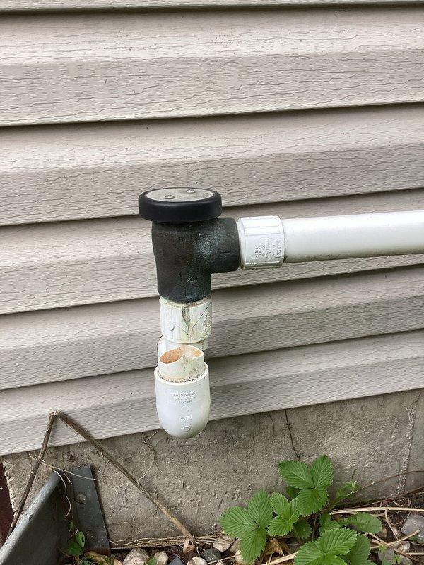 Responded to service call for toilet with no water supply. Upon inspection, discovered exterior water supply line feeding the fixture had sustained damage to the PVC piping system. The vertical supply pipe section showed visible breakage and compromise to the pipe integrity. Identified the affected area on the building's exterior wall where the horizontal supply line transitions through a 90-degree elbow connection before the damaged vertical section. The break in the pipe was preventing water from reaching the toilet fixture on the main floor, resulting in the reported no-water condition.