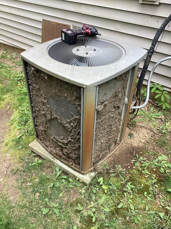 Completed one-time planned maintenance on a 20-year-old outdoor air conditioning condenser unit. The system was operational upon arrival as required for scheduled maintenance service. Performed thorough inspection revealing heavy accumulation of dirt, debris, and organic matter on exterior grilles and significant deterioration of internal components including visible rust and corrosion on contactor/relay switch, along with moisture damage and debris buildup in electrical compartment. Documented unit condition with photographs showing weathered exterior panels, soiled protective grilles, corroded electrical components, and compromised interior compartment with dirt and soil accumulation.
