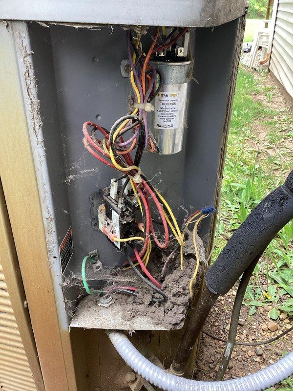 Completed one-time planned maintenance on a 20-year-old outdoor air conditioning condenser unit. The system was operational upon arrival as required for scheduled maintenance service. Performed thorough inspection revealing heavy accumulation of dirt, debris, and organic matter on exterior grilles and significant deterioration of internal components including visible rust and corrosion on contactor/relay switch, along with moisture damage and debris buildup in electrical compartment. Documented unit condition with photographs showing weathered exterior panels, soiled protective grilles, corroded electrical components, and compromised interior compartment with dirt and soil accumulation.