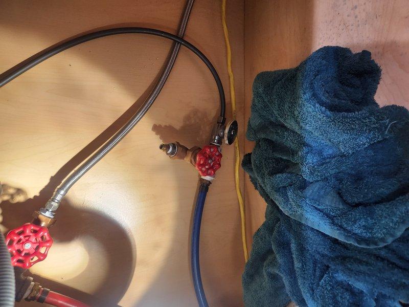 Responded to first-time service call to investigate reported issues allegedly related to improper winterization from previous year. Conducted thorough inspection of plumbing system, focusing on water supply lines, shut-off valves, and associated fixtures in cabinet area. Documented existing conditions with photographs showing HSV30D ASHWORTH1WS system component with visible identification label, as well as under-sink plumbing configuration featuring red wheel-style shut-off valves, braided stainless steel supply lines, and PEX tubing connections. Findings will be discussed with management for review and determination of any corrective action needed.