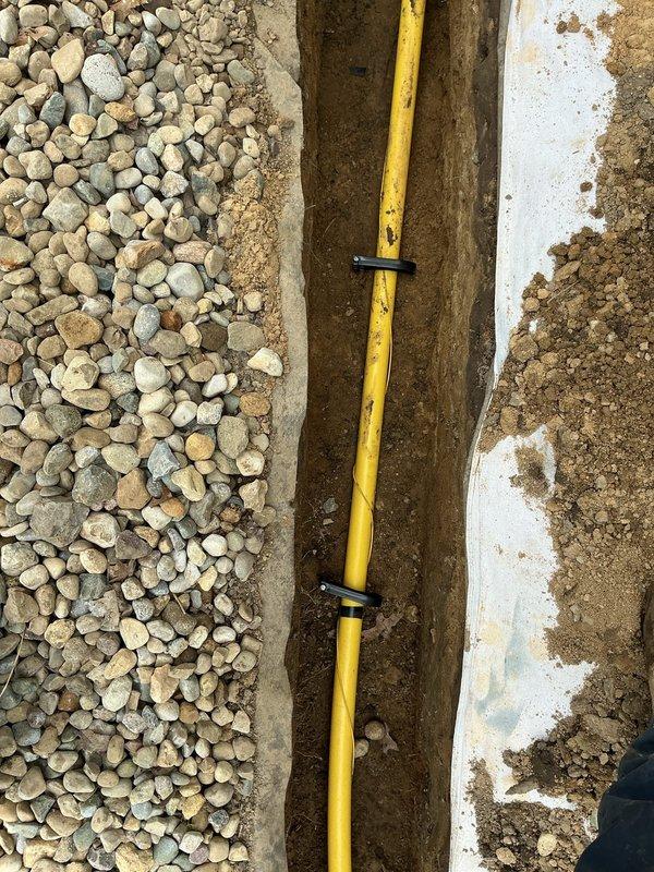 Obtained utility locate clearance and installed approximately 90 feet of 1-1/2" gas line from the meter location on the north end of the structure to the equipment pad in the backyard. Excavated trench to proper depth per code requirements, secured gas line with appropriate brackets, and backfilled trench upon completion of installation.