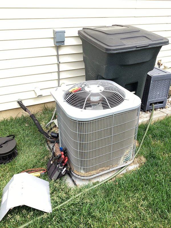 Performed comprehensive cooling system tune-up on residential air conditioning unit. System was found operating properly with no functional issues reported. Exterior inspection revealed moderate accumulation of debris, dirt, and organic material around base and wire guard assembly, which was documented photographically. Cleaned condenser coils, removed debris buildup from unit perimeter, and verified proper airflow through fan assembly. Inspected refrigerant lines, electrical connections, and mounting pad for integrity. All components tested within normal operating parameters with no immediate concerns identified regarding long-term system performance.