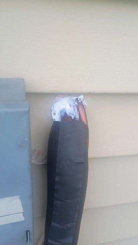 Responded to service call regarding unsealed penetration around refrigerant lines and loud noise from outdoor unit during startup and shutdown. Inspected interior wall penetration where copper refrigerant lines enter building and confirmed opening was not properly sealed, allowing potential air infiltration and energy loss. Documented condition with photos showing exposed cavity around copper tubing. Examined exterior refrigerant line set and observed black foam pipe insulation on copper lines at exterior wall, with exposed copper visible at top section. Evaluated outdoor condensing unit operation and documented reported thunk noise during compressor cycling, which may indicate refrigerant pressure equalization or potential mechanical issue requiring further diagnosis.