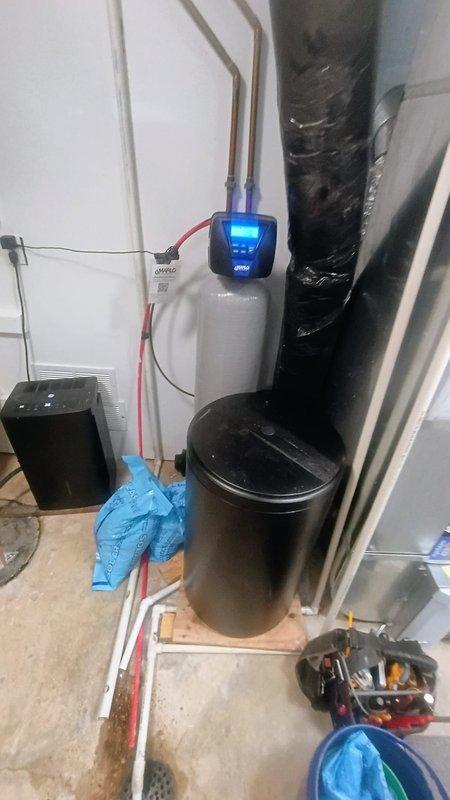 Installed new water softener system in residential utility room, including complete setup of dual-tank filtration unit with digital control panel and copper supply line connections. System was fully plumbed, tested for proper operation, and left in working condition with illuminated display confirming active status.