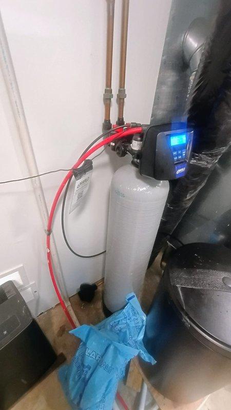 Installed new water softener system in residential utility room, including complete setup of dual-tank filtration unit with digital control panel and copper supply line connections. System was fully plumbed, tested for proper operation, and left in working condition with illuminated display confirming active status.